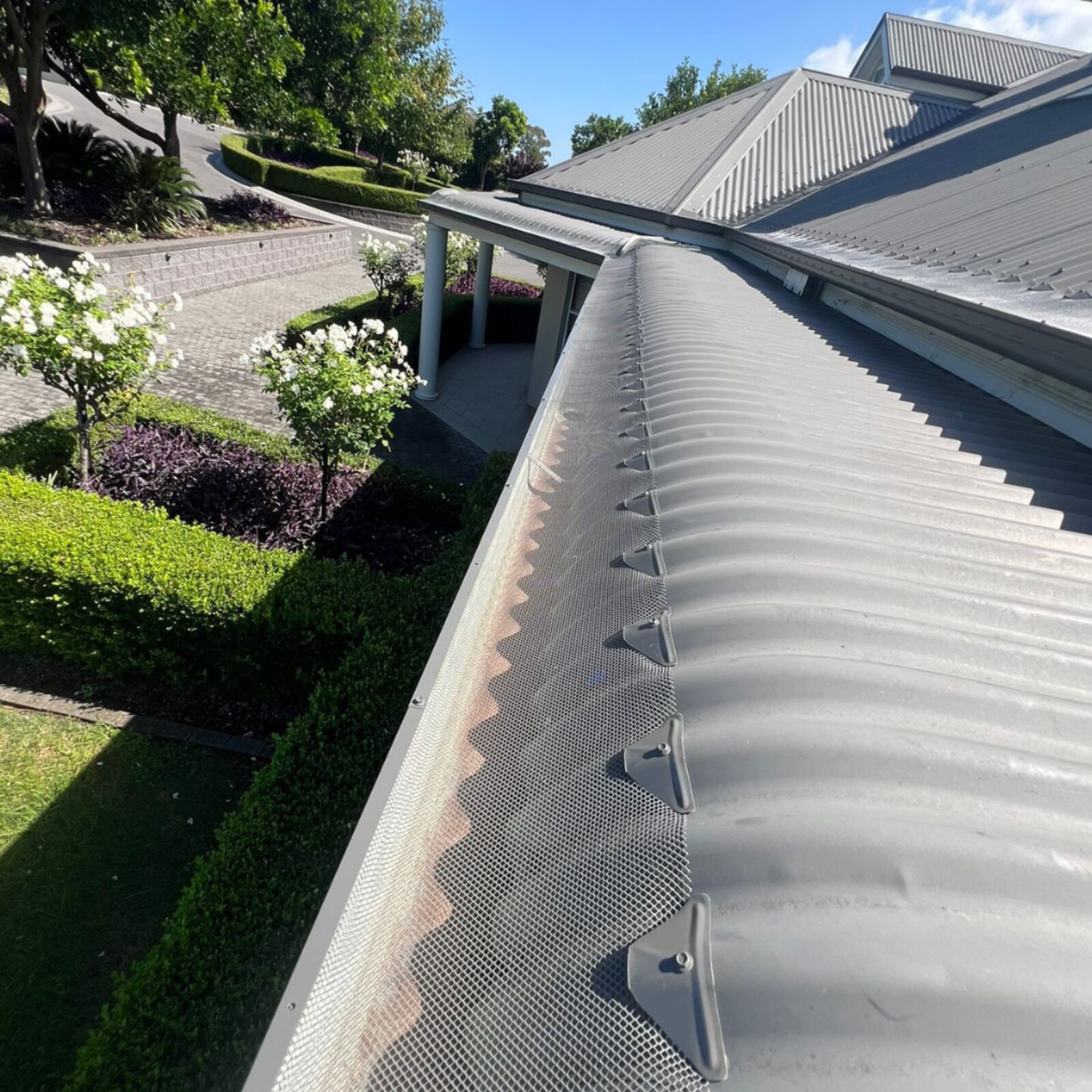 Long curved Colorbond roofline sealed with colour-matched gutter mesh and saddles after installation, Cecil Park