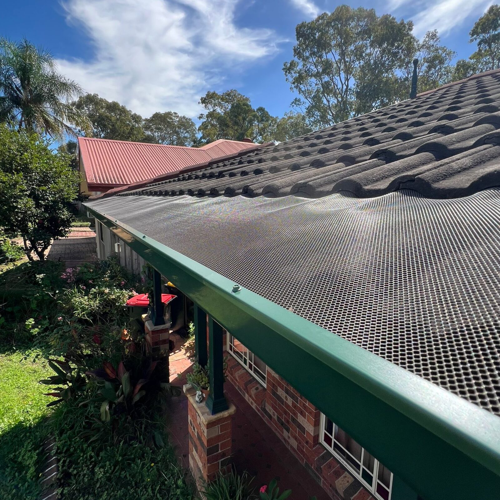 Same green Colorbond gutter sealed with black gutter mesh and colour-matched trim after installation