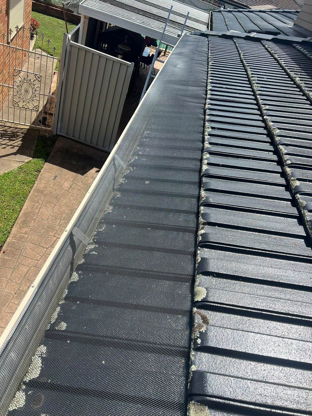 Black gutter guard mesh installed on a tiled roof
