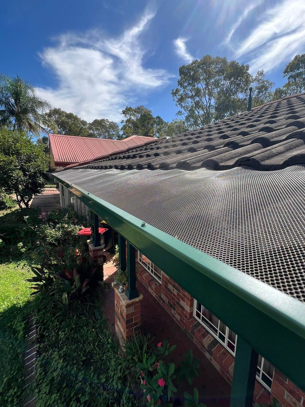 Colour-matched gutter mesh along a tiled roof and gutter line