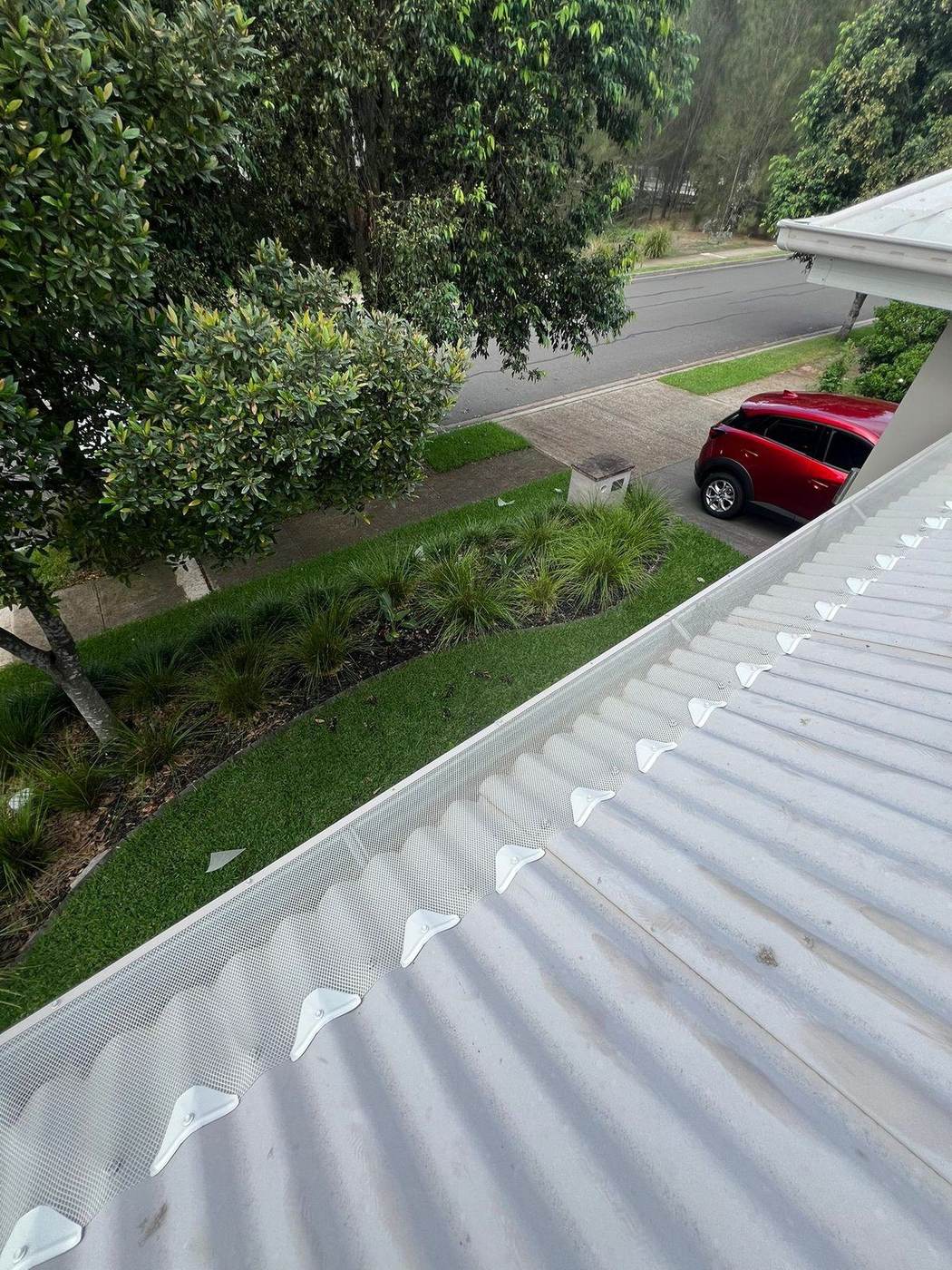 White gutter guard mesh installed on a corrugated metal roof