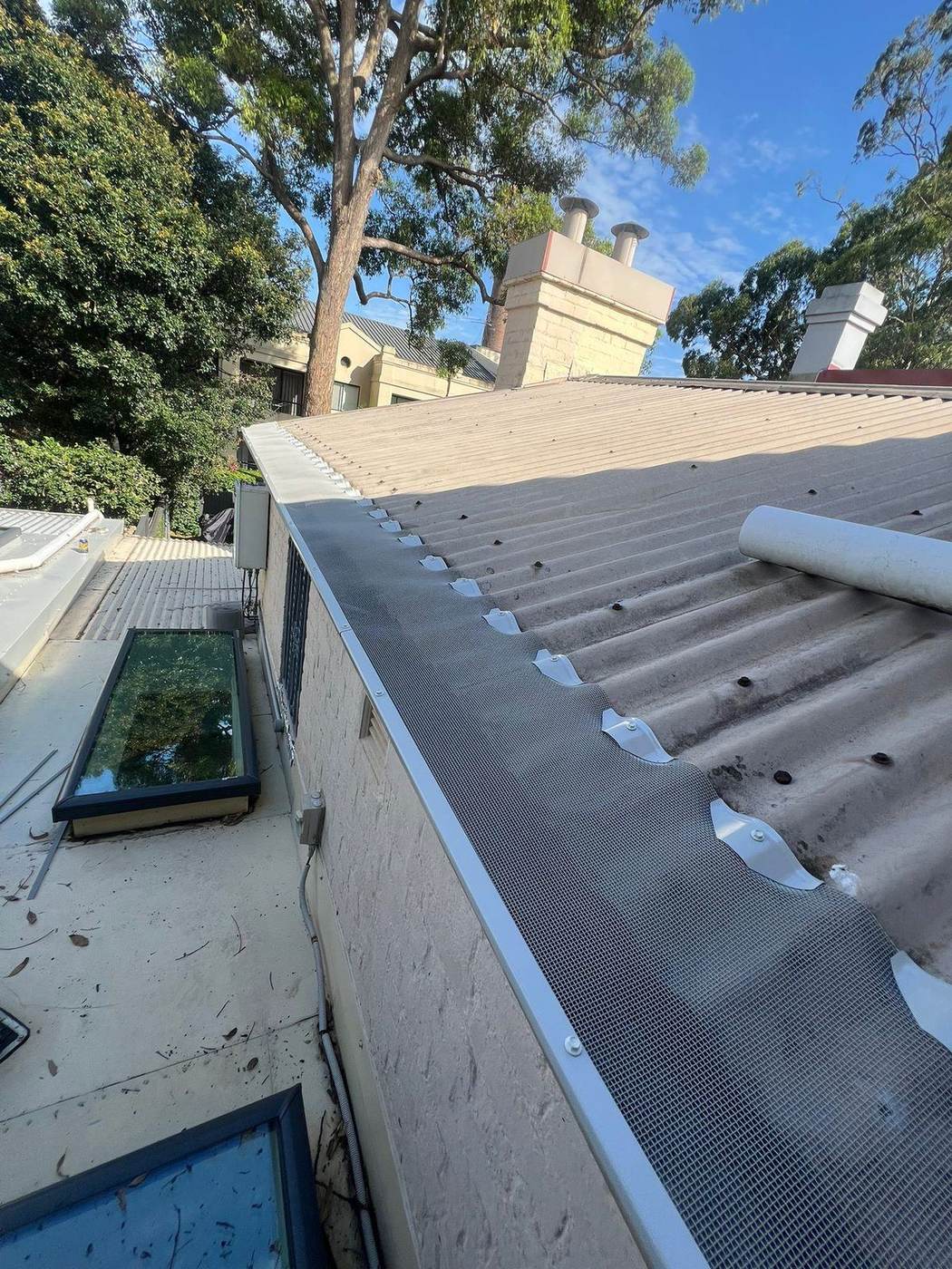 Colour-matched gutter mesh on a terracotta tiled roof